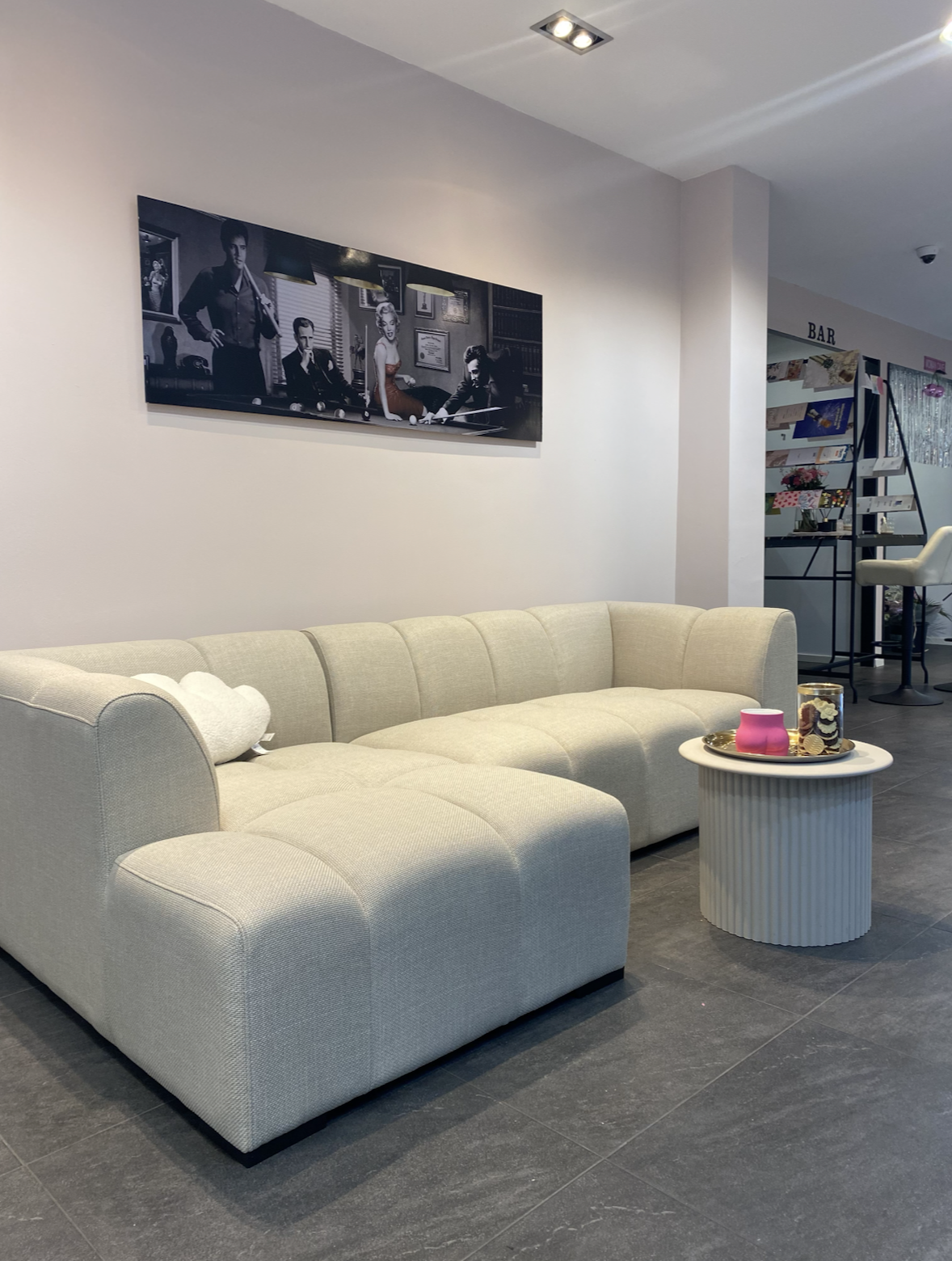 Loungehoek van de salon met zachte bank, gouden accenten en kunst aan de muur